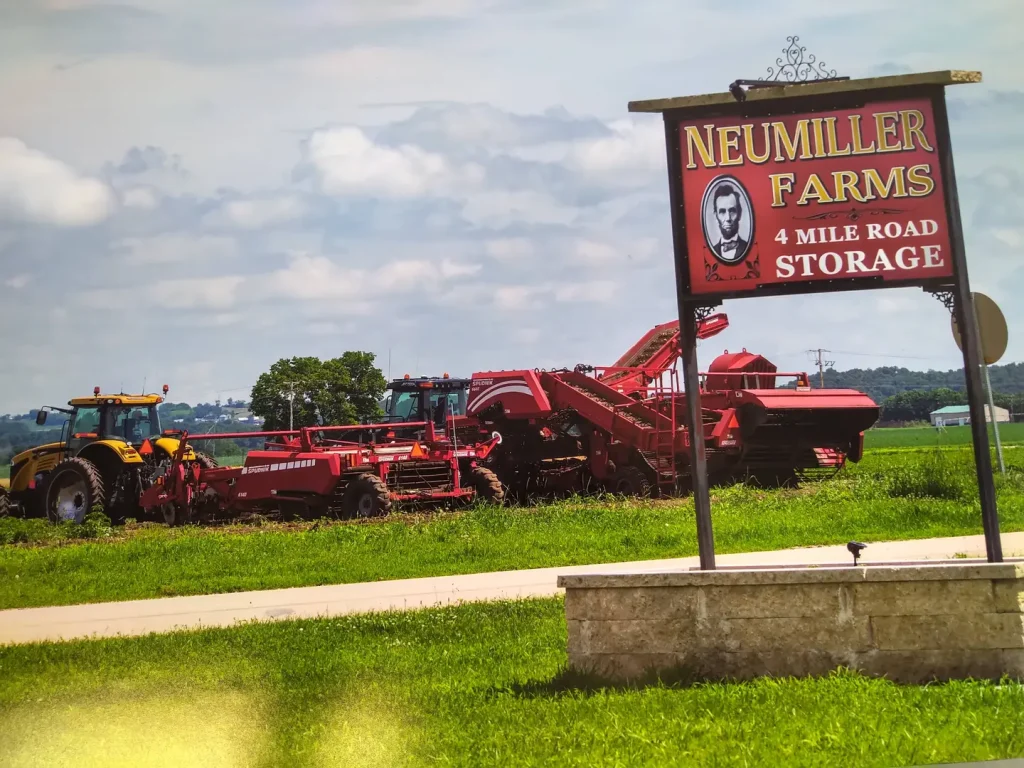 Neumiller Farms road sign that also reads "4 Mile Road Storage" with tractors behind the sign